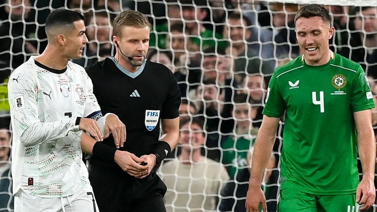Cristiano Ronaldo of Portugal and Dara O'Shea stood either side of match referee during Portugal's match with Republic of Ireland
