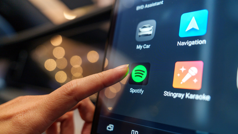 Tapping a Spotify button on a car's digital interface.