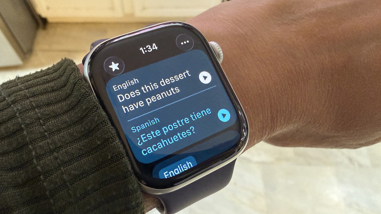 An Apple Watch on wrist showing a translation from English to Spanish.