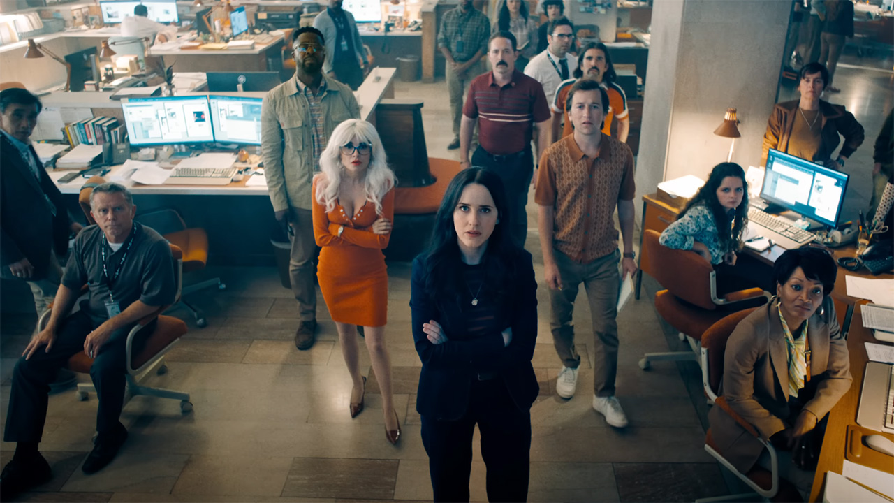 Cat grant, Lois Lane, Steve Lombard, and Jimmy Olsen looking an off-camera screen in The Daily Planet's newsroom in Superman