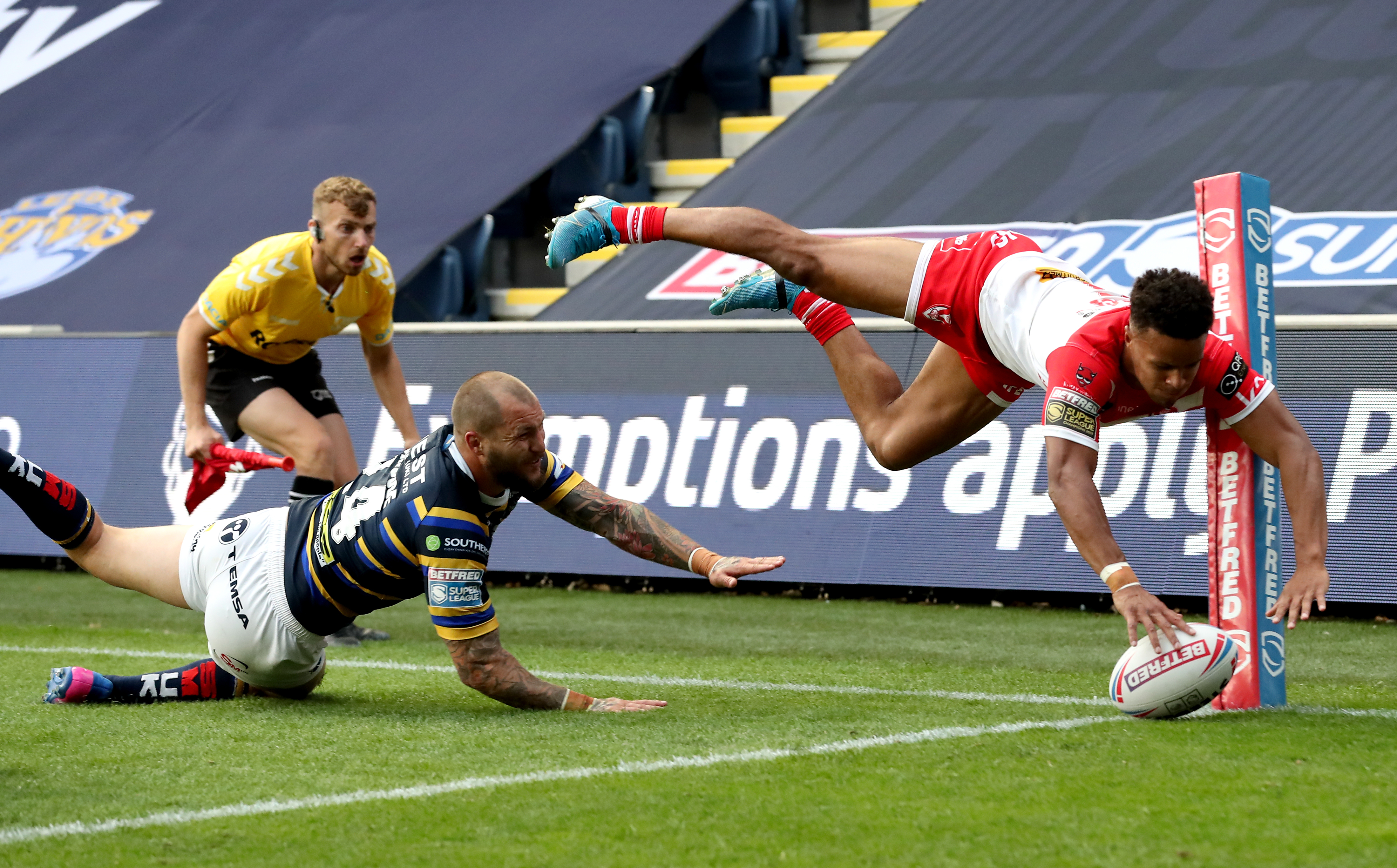 Regan Grace of St Helens scoring a try, evading a tackle from Leeds Rhinos' Luke Briscoe.