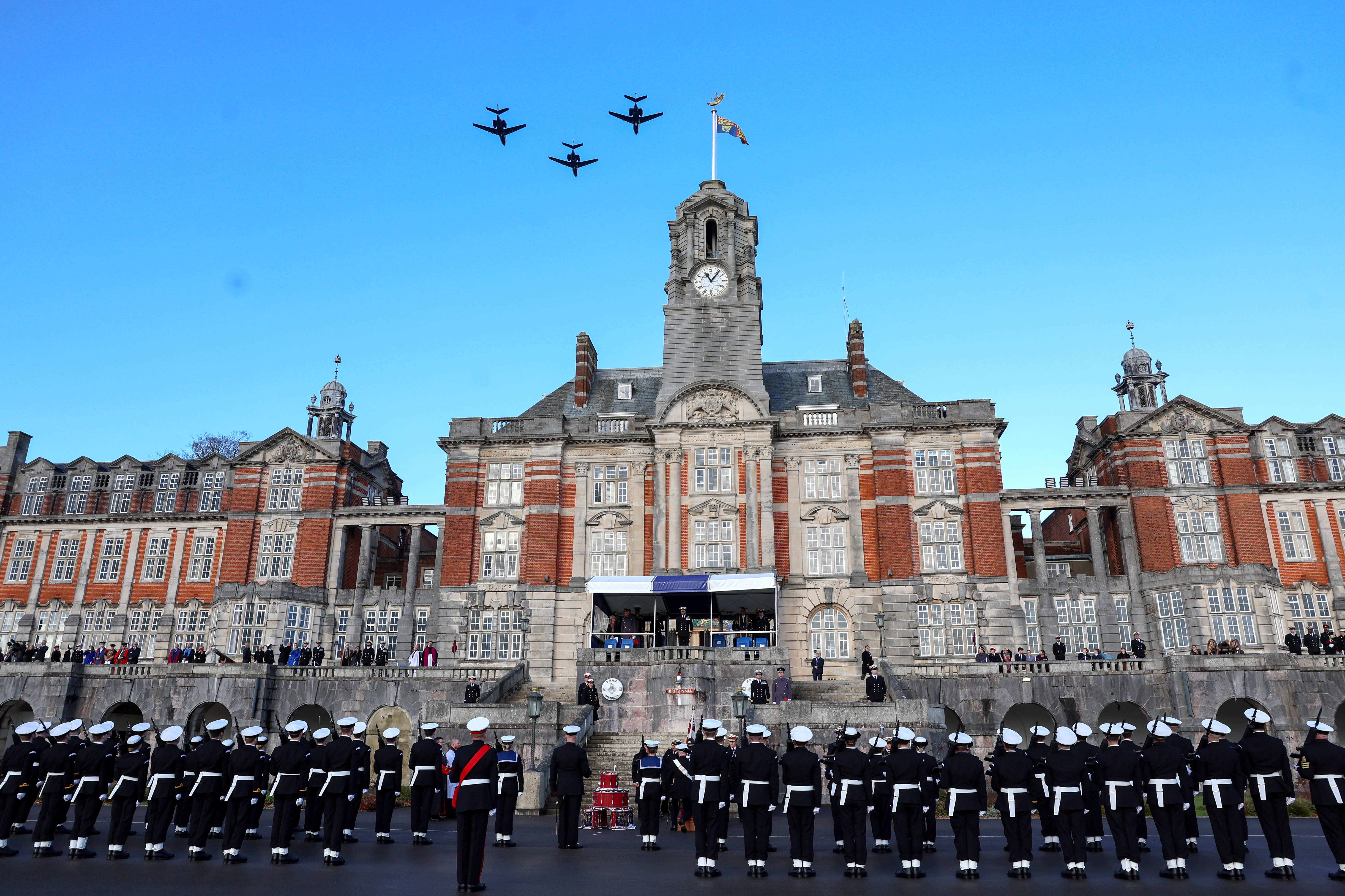 Royal Navy cadets standing at attention during a flypast by three Dassault Falcons at Britannia Royal Naval College.