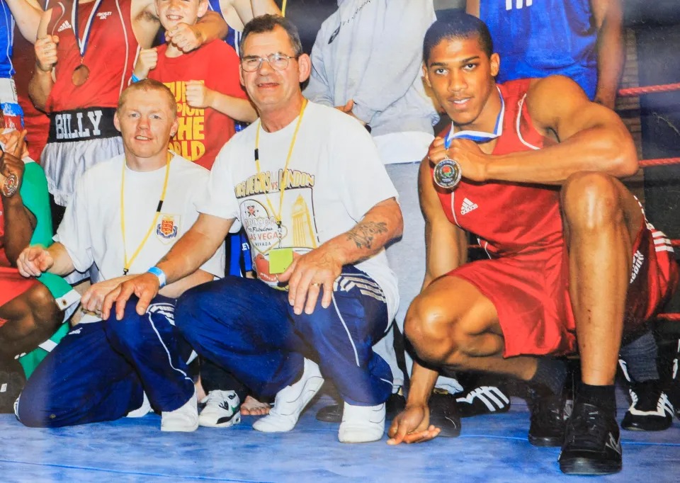 Anthony Joshua holding a medal, Sean Murphy, and John Oliver at an event.