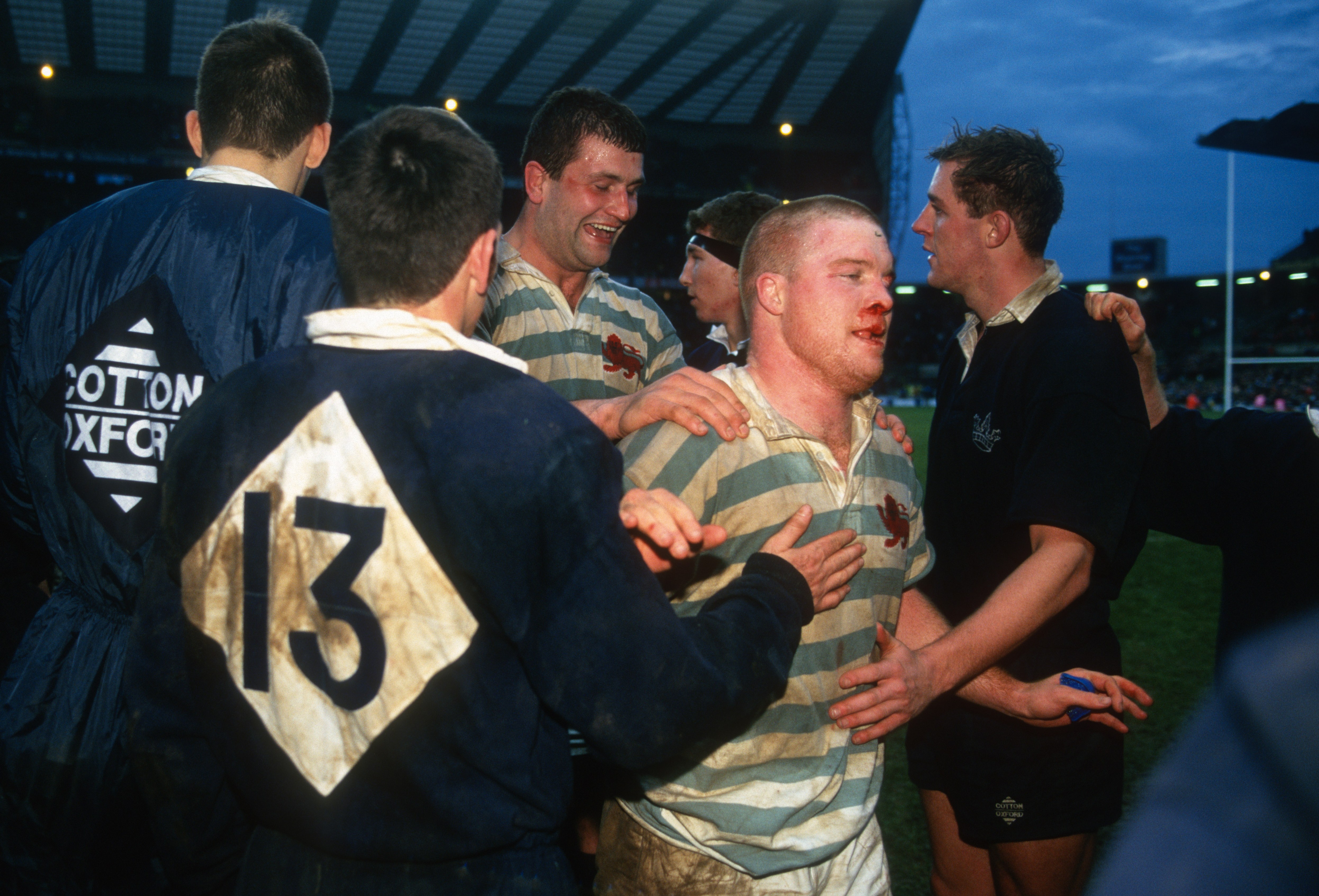 Cambridge University captain Tom Murphy, bloodied from a nose injury, embraced by teammates after the Varsity Match against Oxford University.