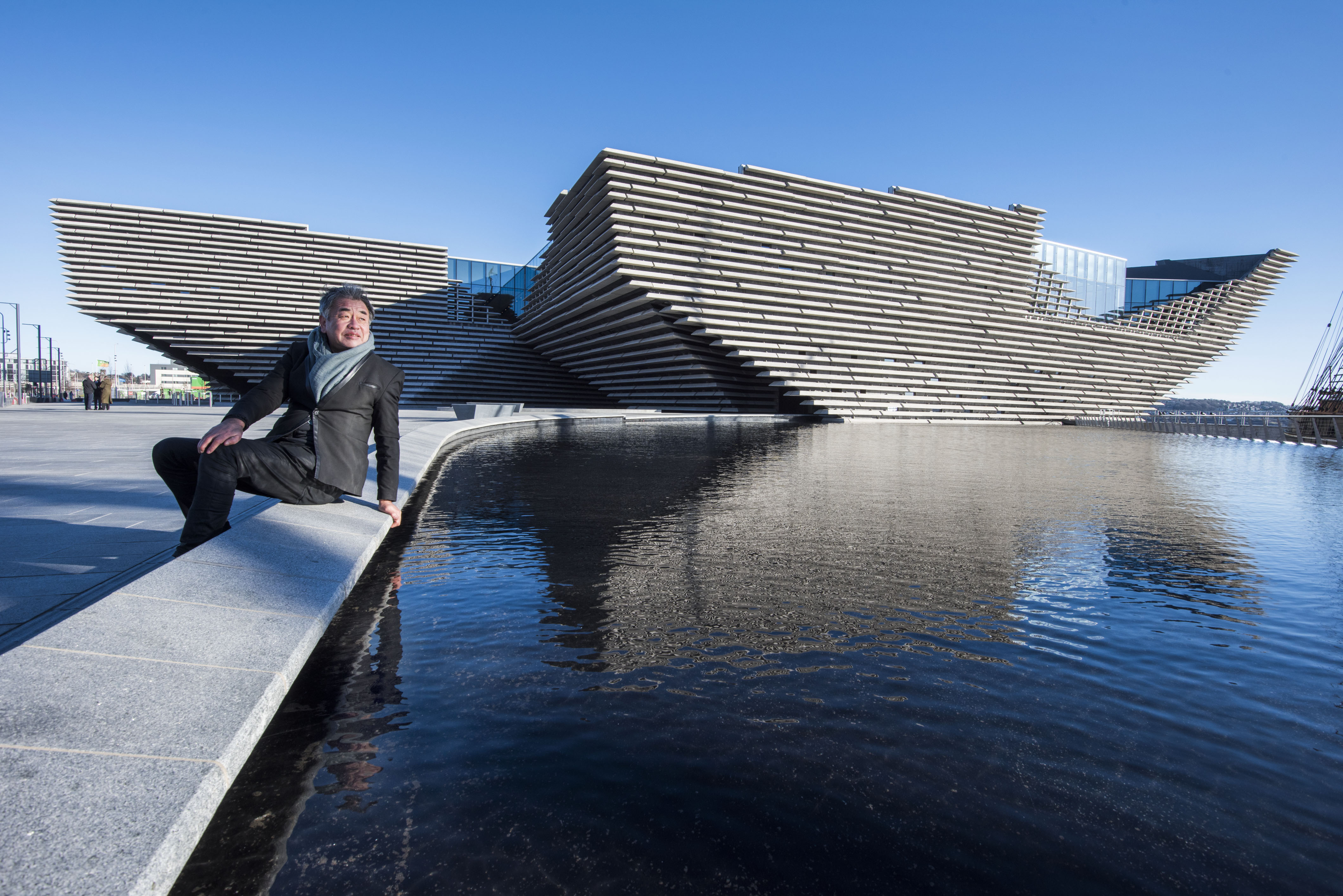 Kengo Kuma seated by water in front of V&A Dundee.