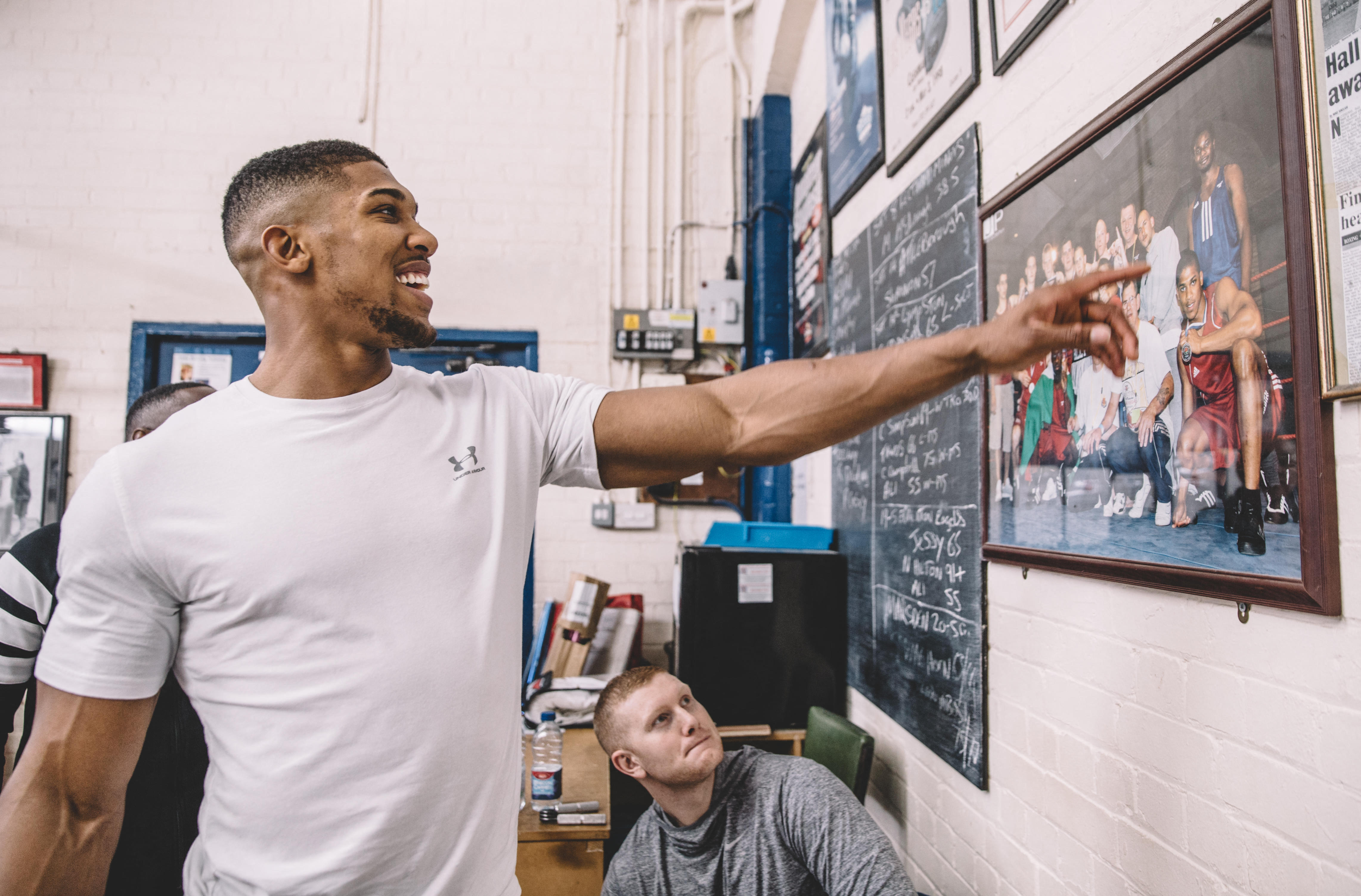 British Heavyweight boxer Anthony Joshua pointing at a framed photo of himself.