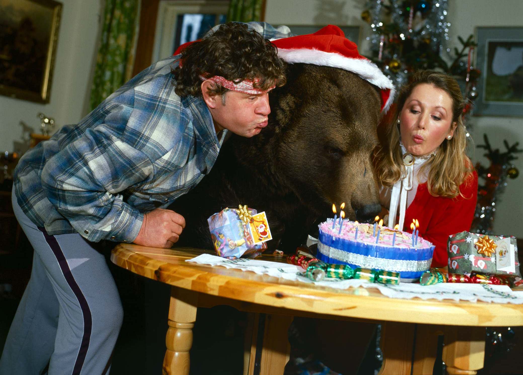 Andy Robin, his wife Maggie, and Hercules the bear blowing out birthday cake candles.