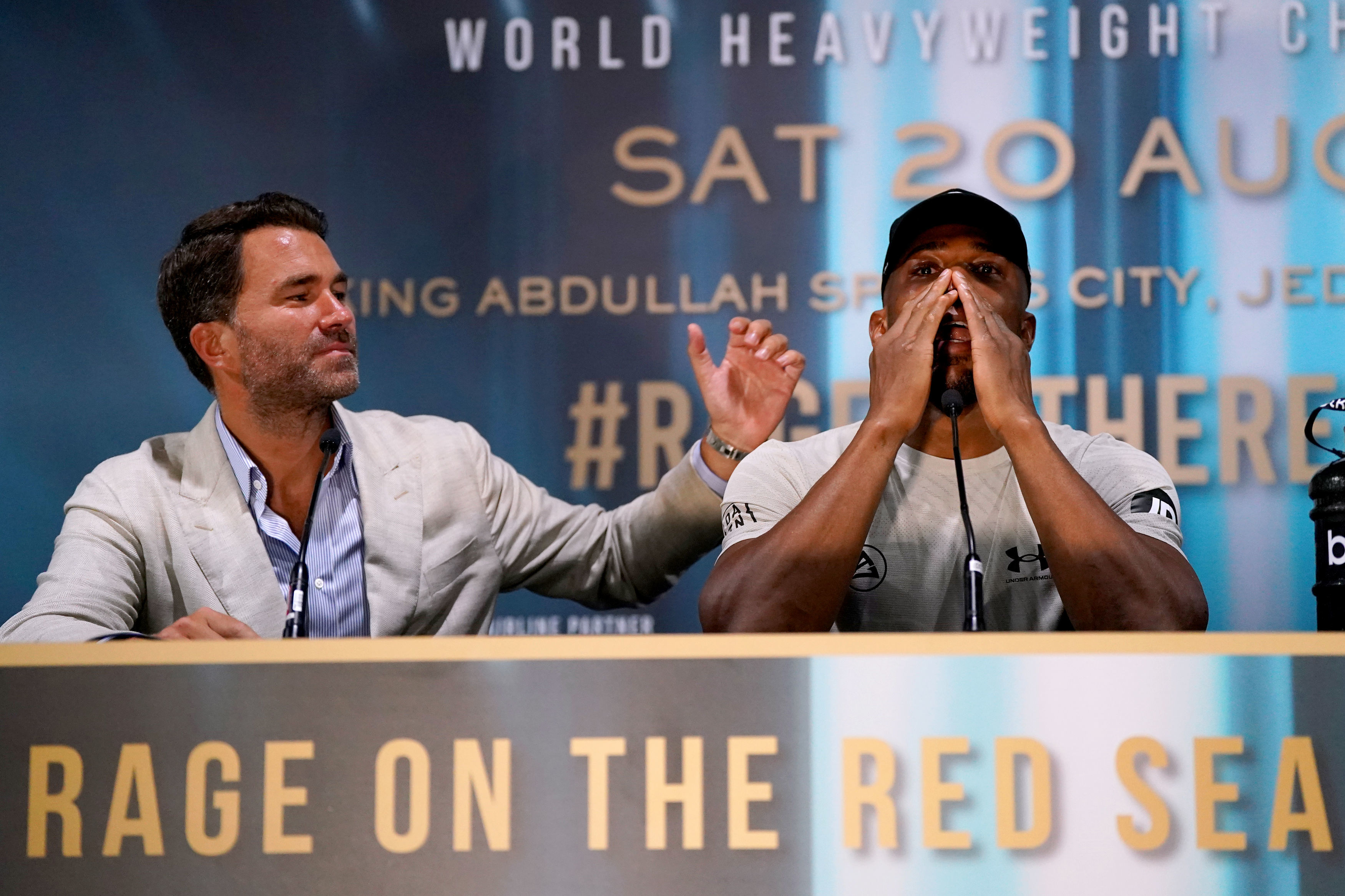 Boxing promoter Eddie Hearn comforts Anthony Joshua at a press conference.