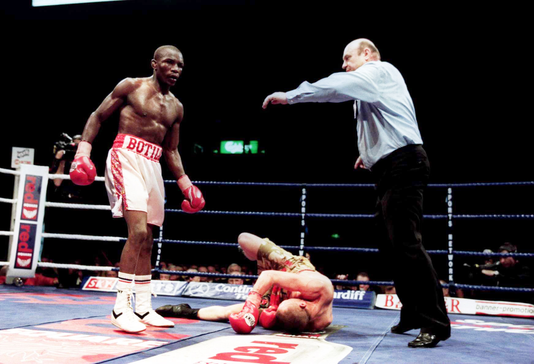 Mbulelo Botile stands over Paul Ingle who is knocked down, with referee Dave Paris nearby.
