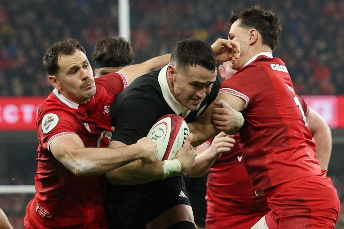 New Zealand's Will Jordan being tackled by two Welsh rugby players.