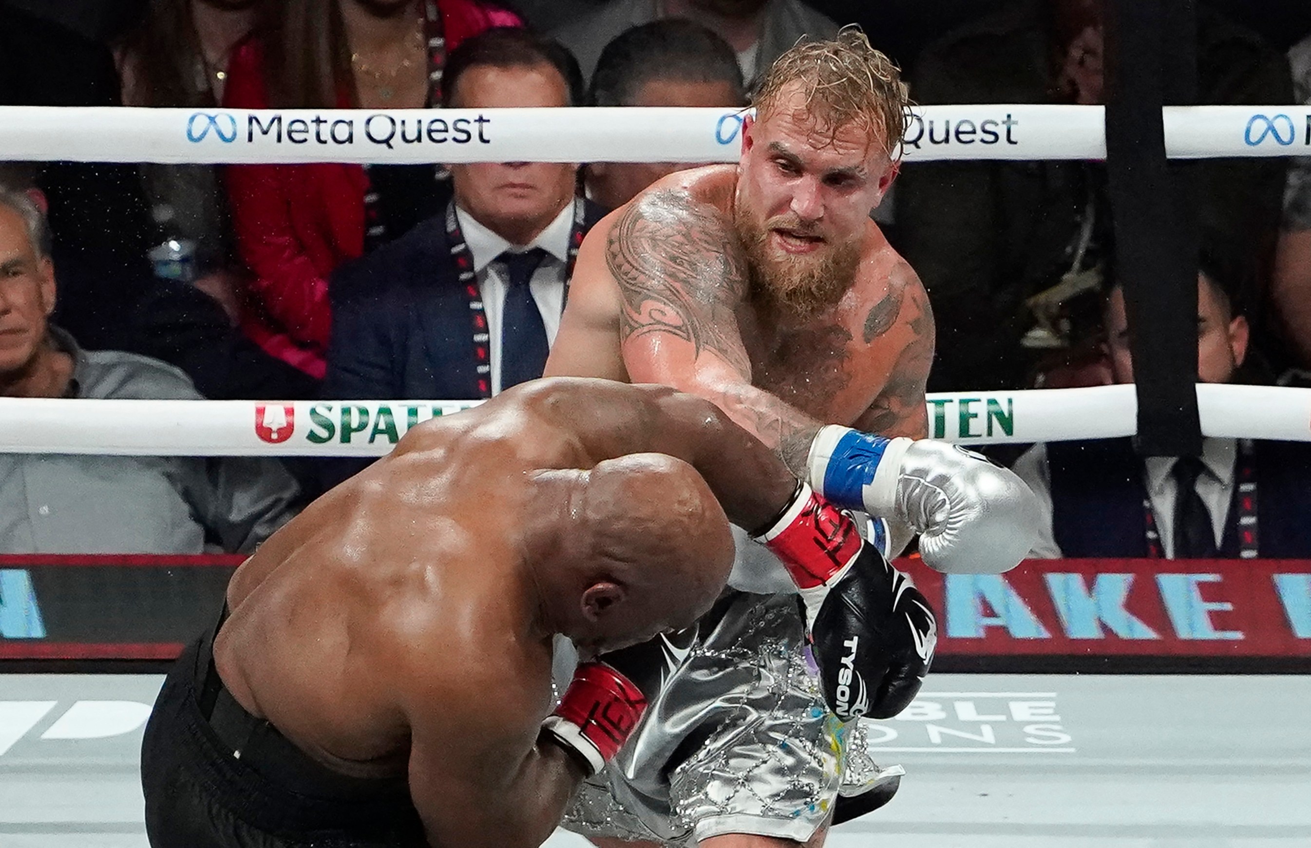 Boxers Mike Tyson and Jake Paul fighting in a boxing ring.