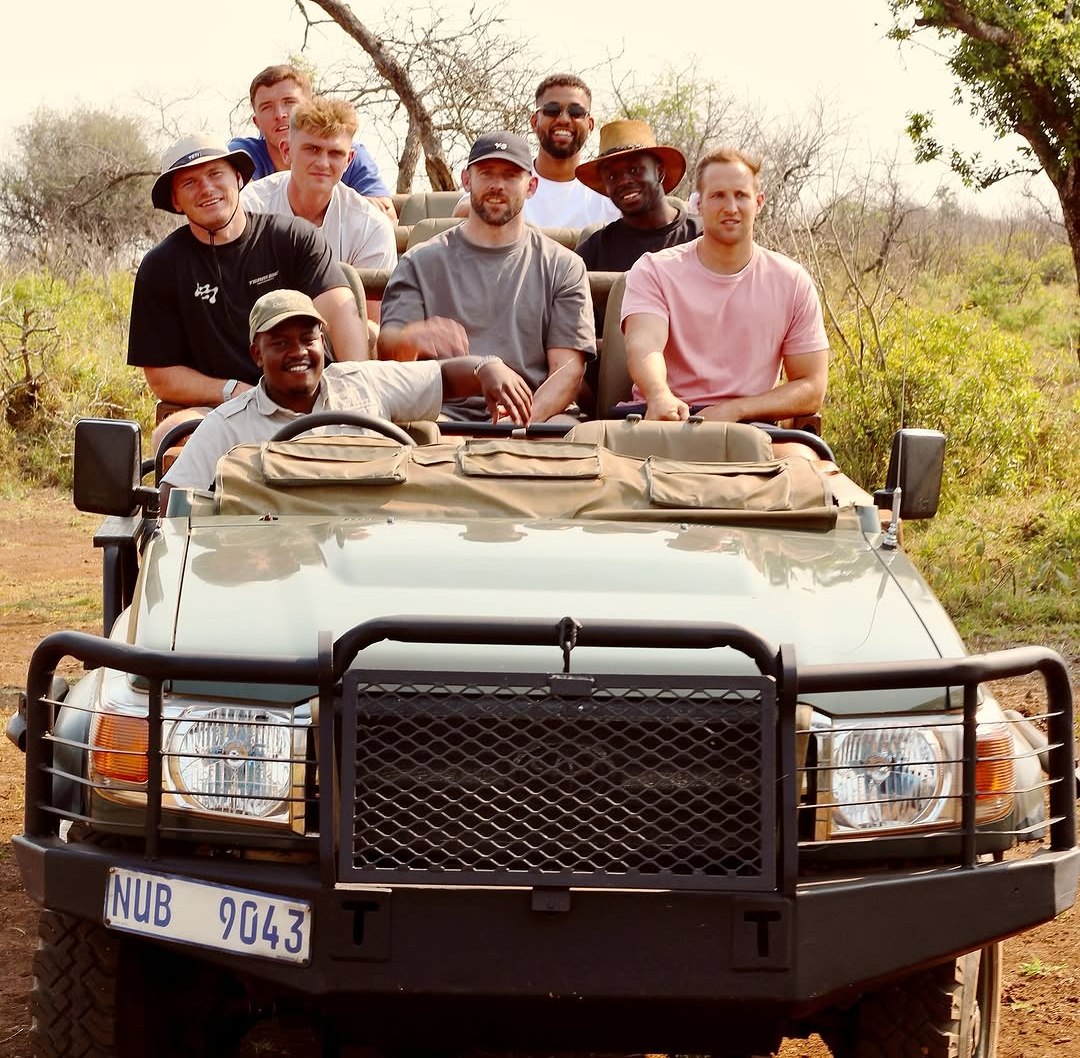 Saracens rugby players and a driver in a safari vehicle during pre-season training camp.