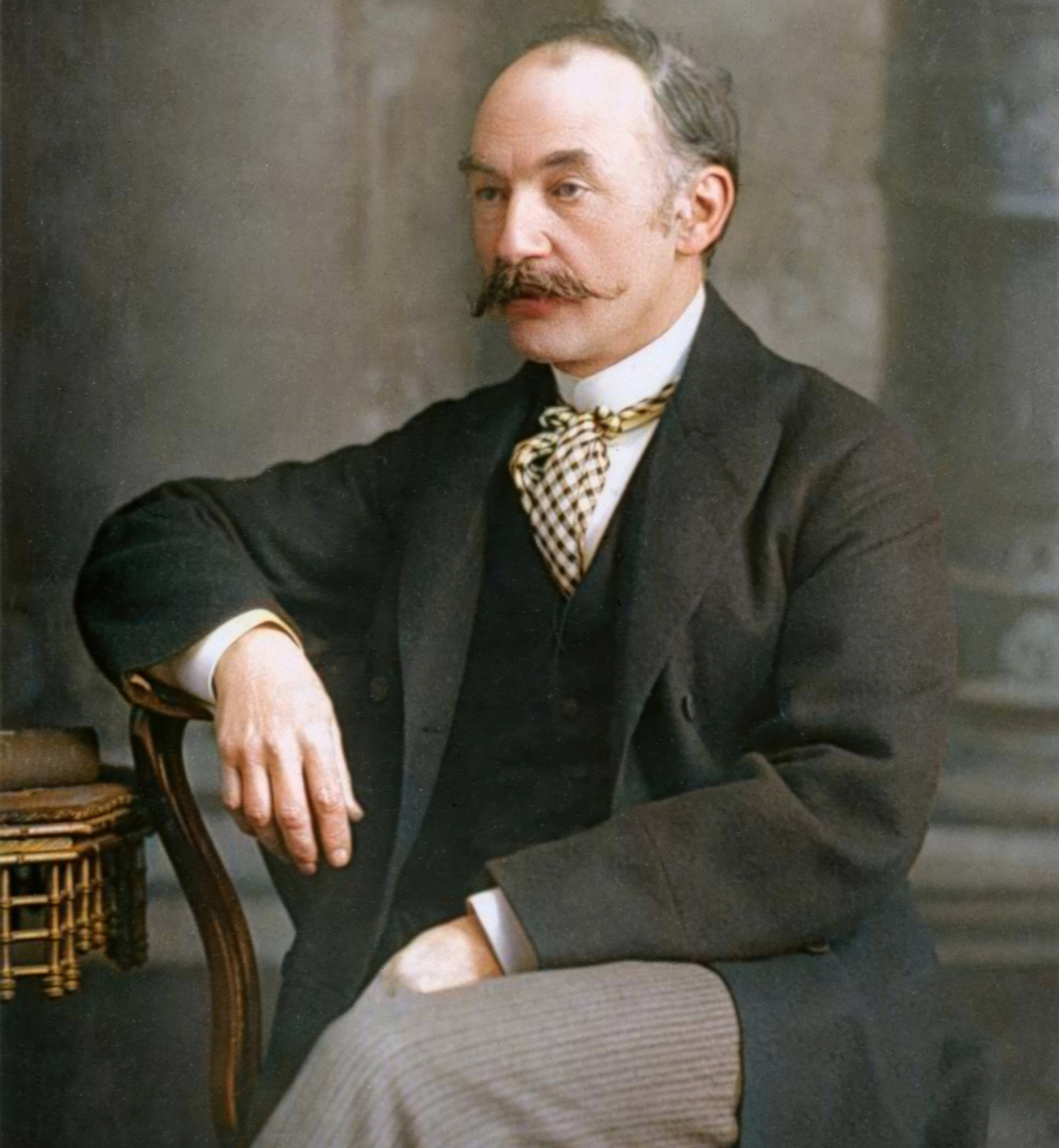 Thomas Hardy, English writer and poet, sitting with his arm resting on a chair, circa 1890.