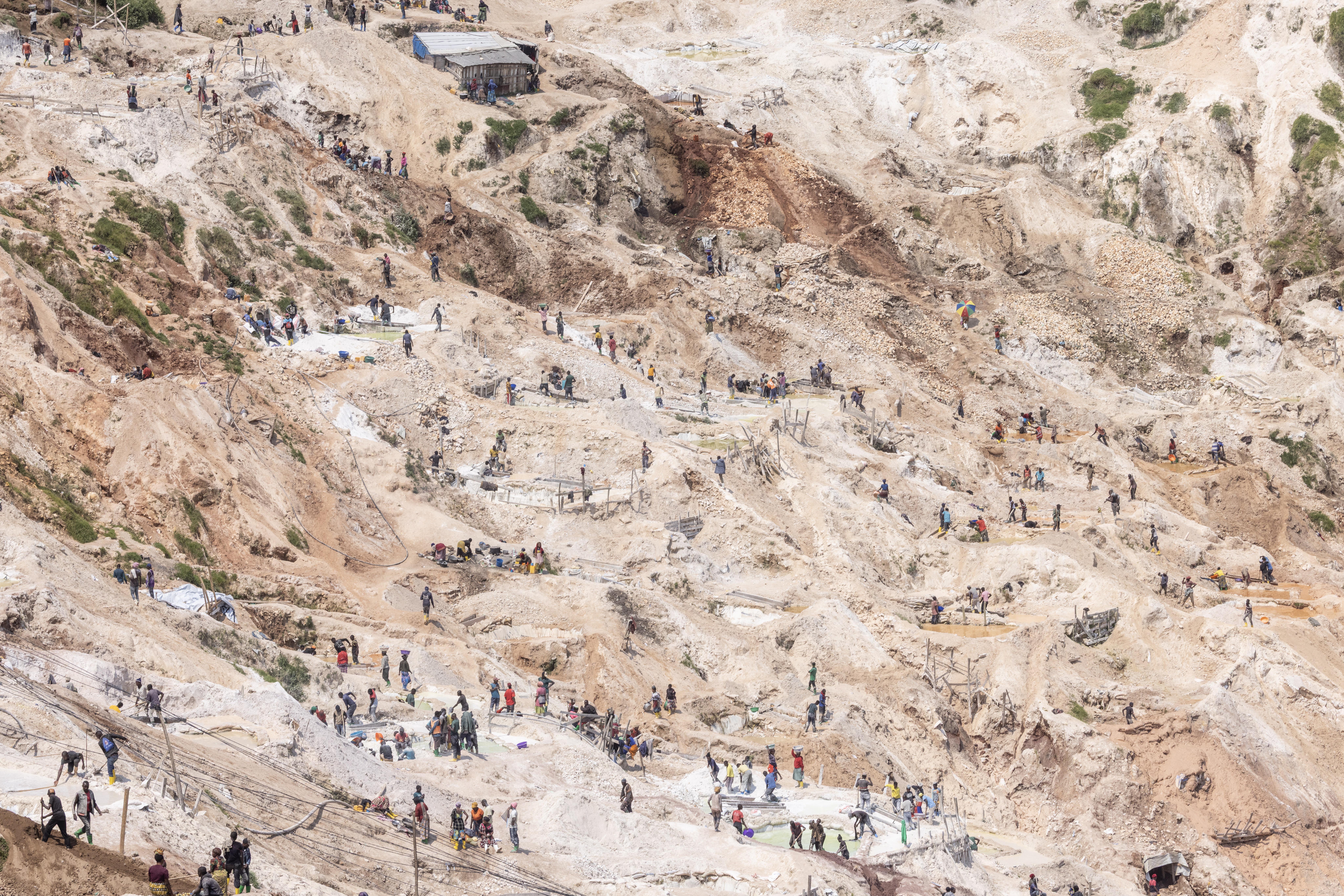 A vast open-pit mine in Rubaya, North Kivu Provence, with many people working across the landscape to extract coltan and manganese.
