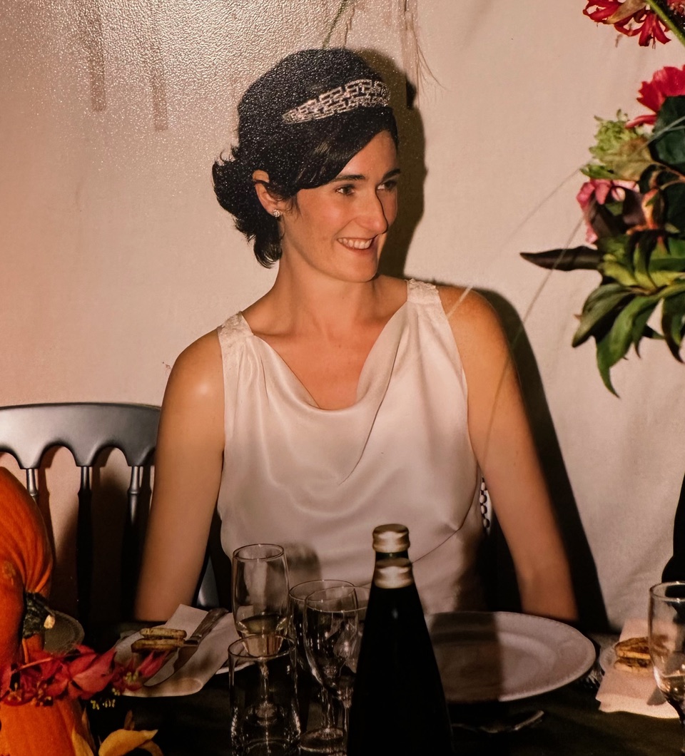 Photographer Harriet Challis at her wedding, smiling and sitting at a dinner table.