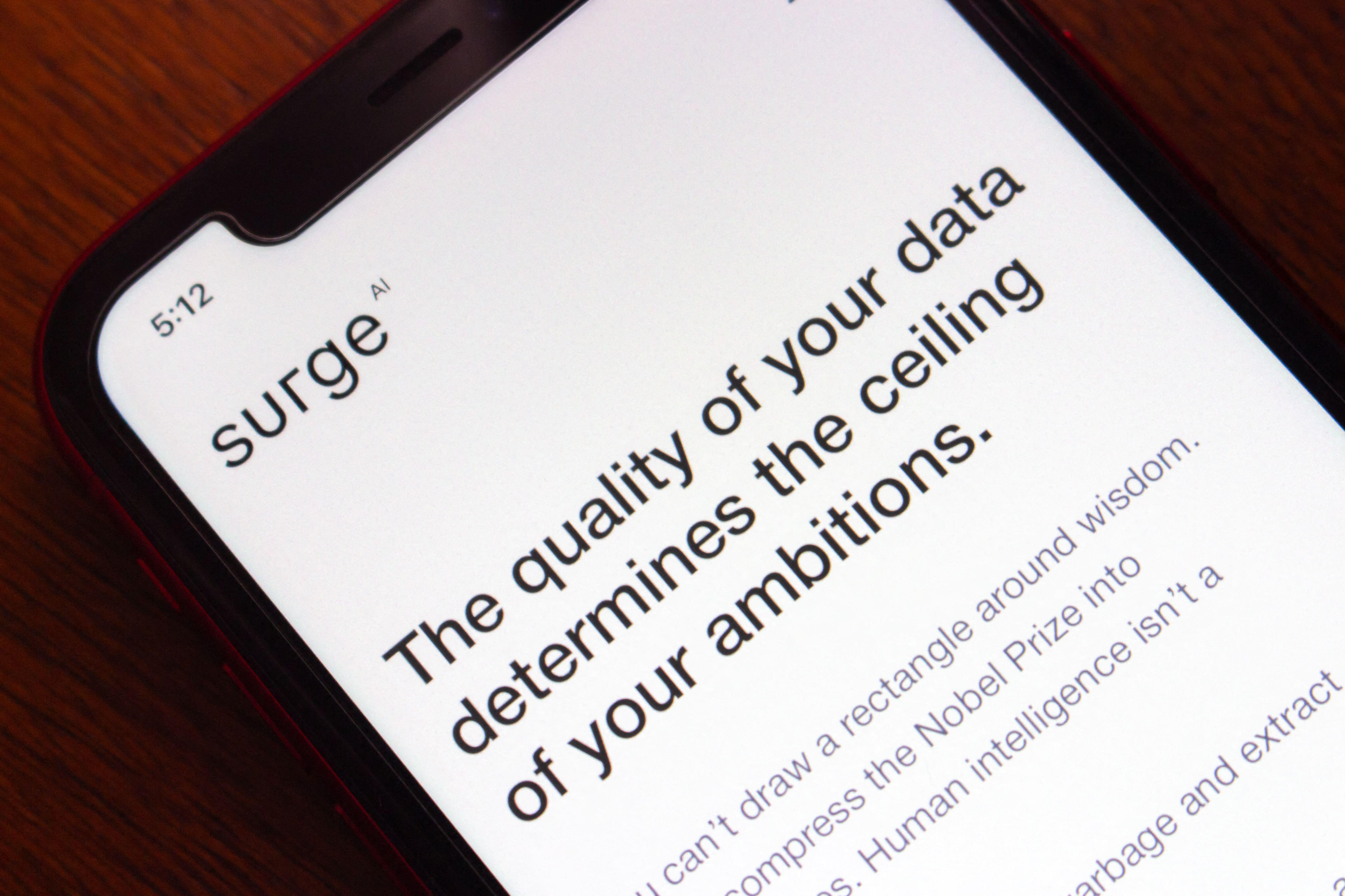 Close-up of a smartphone screen displaying the Surge AI website with the text "The quality of your data determines the ceiling of your ambitions."
