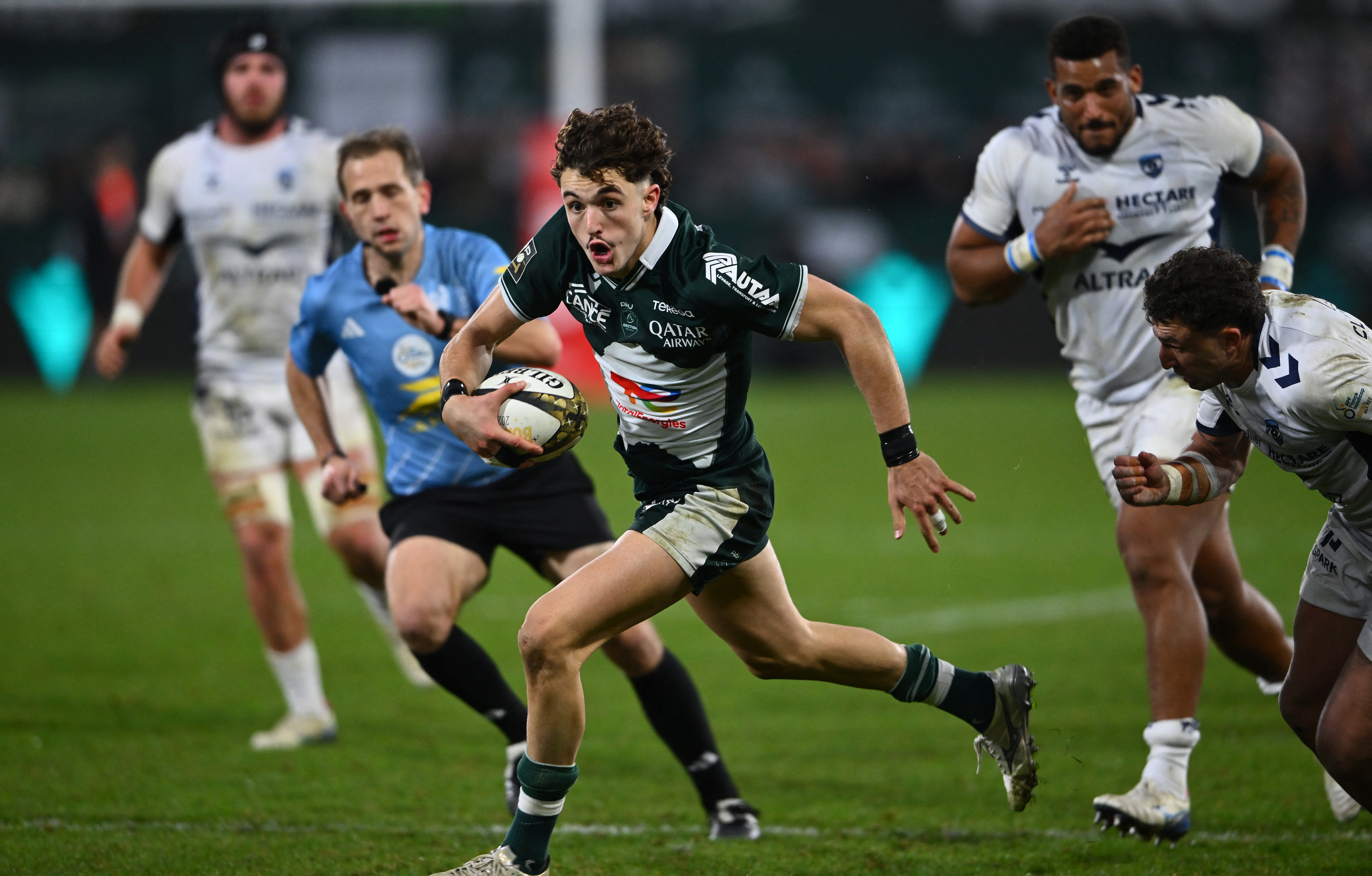Pau's French wing Grégoire Arfeuil (C) running with the ball during a rugby match.