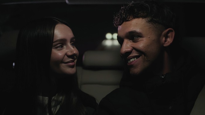 Sarah and Jacob smile at one another in the back of a car in Corriedale
