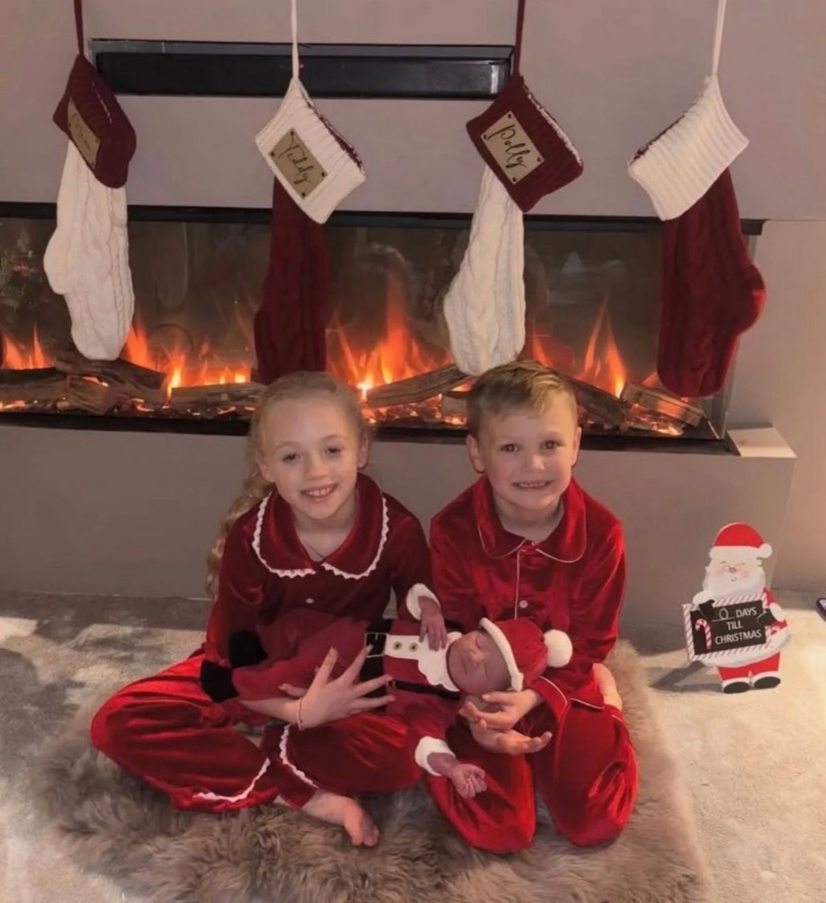 Polly and Teddy in red pyjamas holding Bobby in a santa onesie 