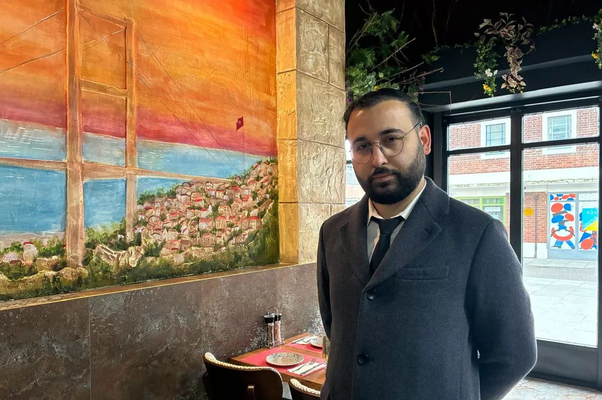Manager Ozan Coban stands next to one of Baba's handmade vistas that shows his home city of Istanbul