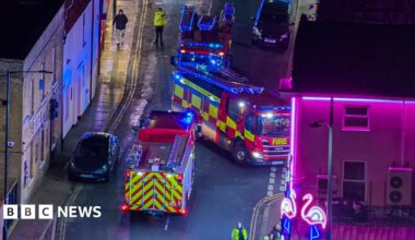Three fire engines blocking a road at night as they respond to an emergency call.
