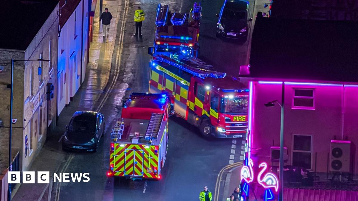 Three fire engines blocking a road at night as they respond to an emergency call.
