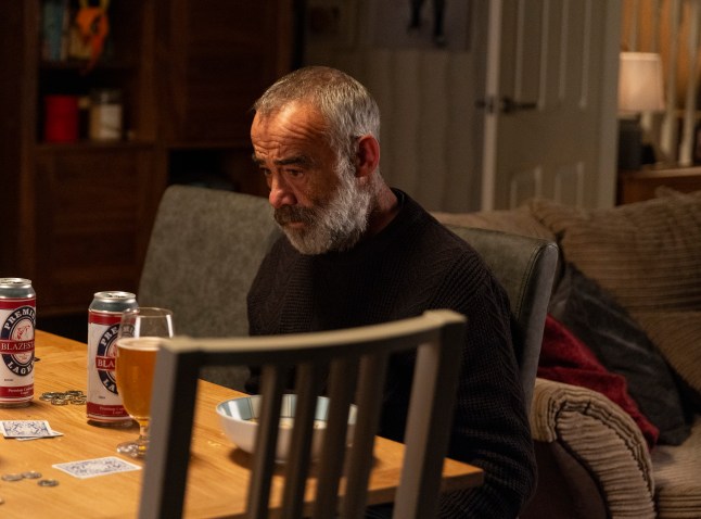 Kevin Webster sitting at his table in Coronation Street