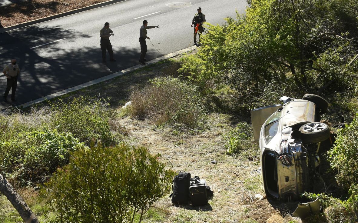Law enforcement officers investigate the scene of Woods' rollover crash in Rancho Palos Verdes, California, in February 2021. Woods <a href=