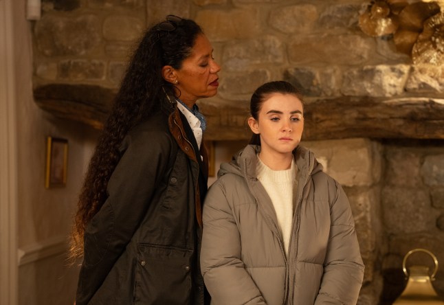 Celia Daniels standing menacingly beside a worried April Windsor in Emmerdale.