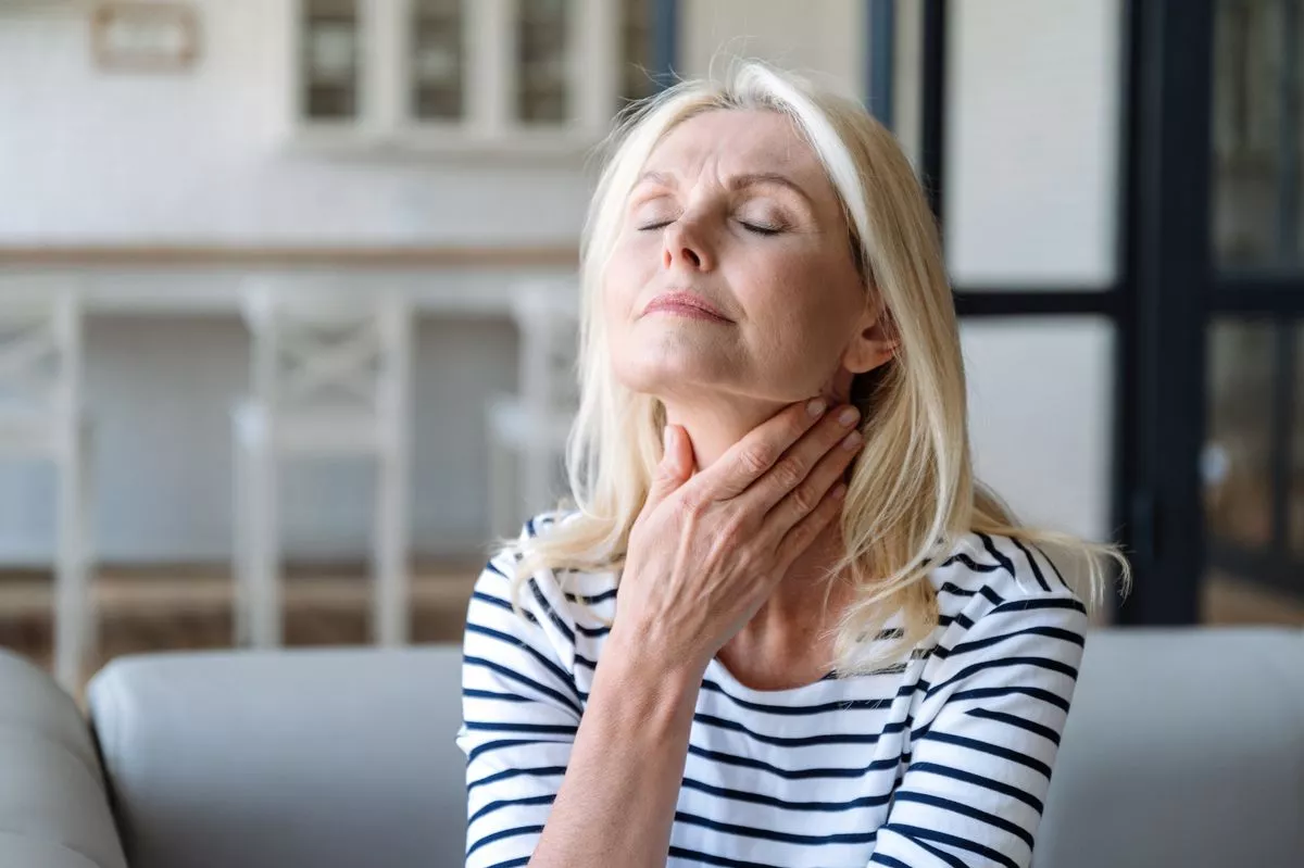 Woman touching sore throat