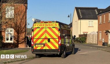 A police forensics van is parked on a residential estate on a sunny day.