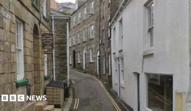 Google Street View image of Polkirt Hill in Mevagissey. It is a narrow single-lane road with double yellow lines on either side. Buildings line the road on both sides.