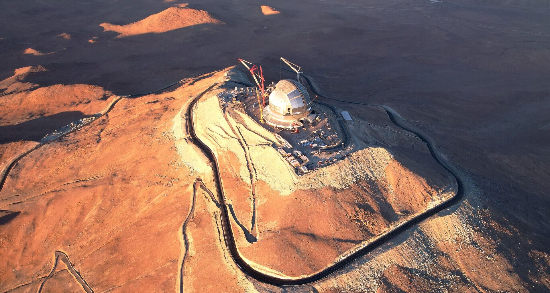 A drone shot showing a metal domed building against a desert peak in Chile