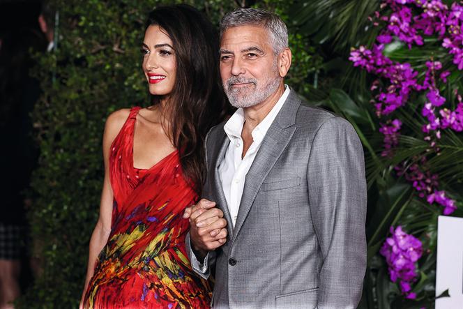 Lebanese-British barrister Amal Alamuddin Clooney wearing an Alexander McQueen dress and her husband/American actor and filmmaker George Clooney arrive at the Los Angeles Premiere Of Universal Pictures' 'Ticket To Paradise,' held at Regency Village Theatre on October 17, 2022 in Westwood, Los Angeles, California.