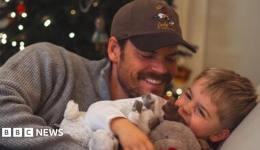 Ryan smiling and tickling his giggling young son Leo on the sofa