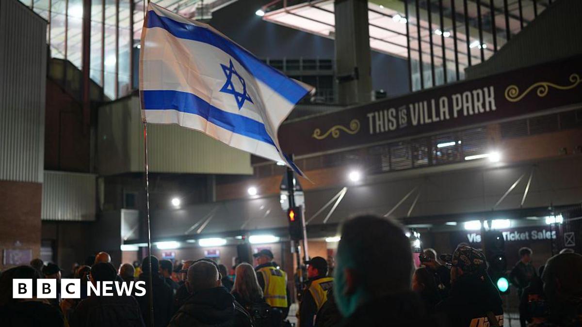 An Israeli flag held by pro-Israeli supporters outside Villa Park ahead of the game on 6 November 2025. It is night and police are escorting them