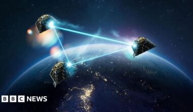 An artist's impression of three satellites in orbit above part of the Earth which is in darkness. The satellites' connection to each other is illustrated by laser-like rays forming a triangle between them.