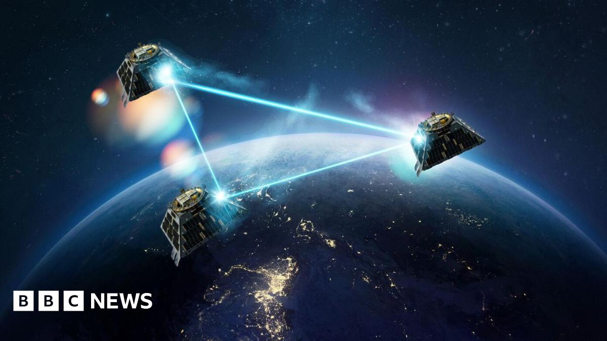 An artist's impression of three satellites in orbit above part of the Earth which is in darkness. The satellites' connection to each other is illustrated by laser-like rays forming a triangle between them.