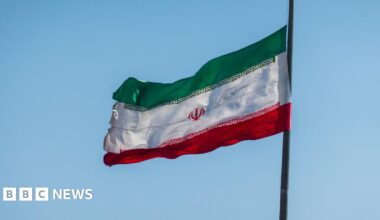 Iranian flag flies against a blue sky.