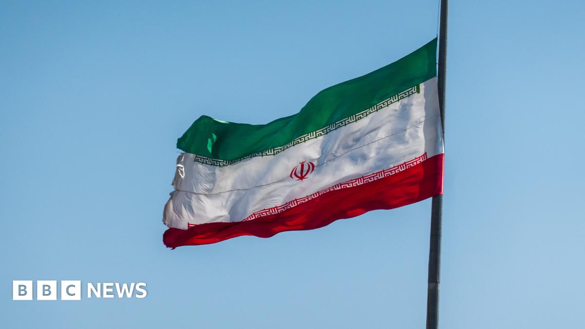 Iranian flag flies against a blue sky.