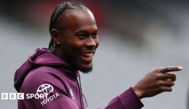 Jofra Archer smiles and points with his right hand