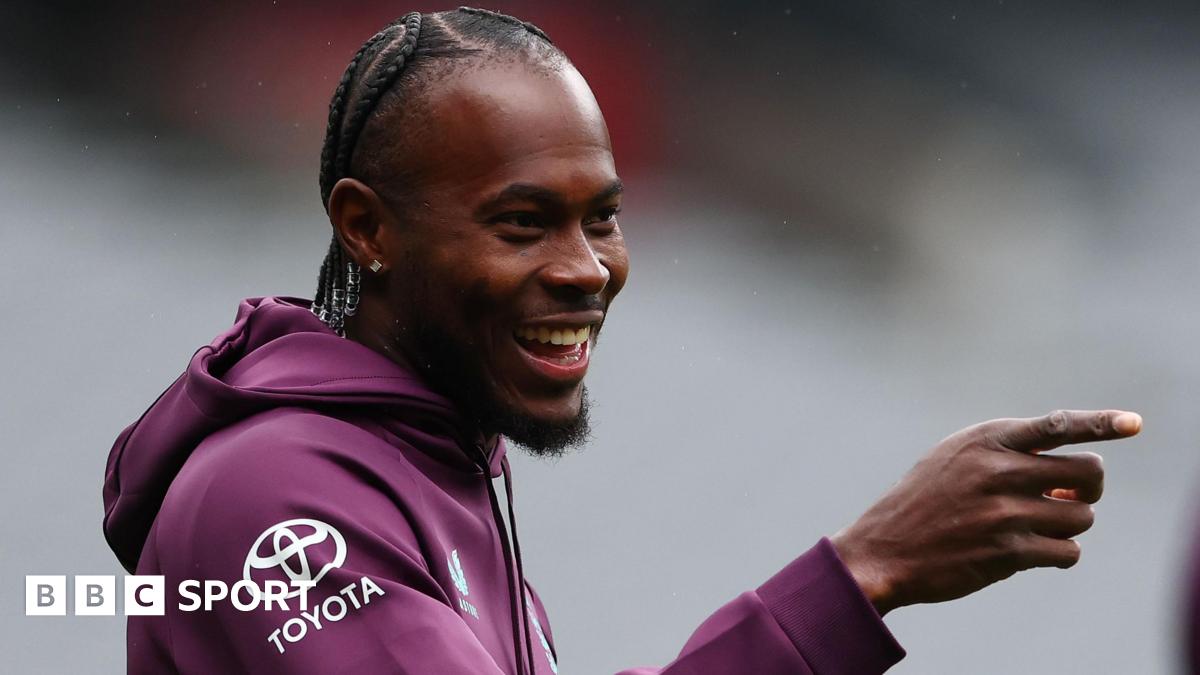 Jofra Archer smiles and points with his right hand