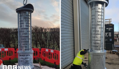 On the left is a picture of the mining lamp being installed in Ferryhill with protective orange fencing around it. On the right the lamp is receiving the final touches before being transported to Ferryhill. There is a man in a high-vis vest and black trousers who is on his knees beside the lamp.