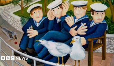 Four men dressed in blue sailor suits and hats are siting smoking on a bench in a park. Two seagulls are  perched on a rail in front of them and one has its beak open and appears to be squawking.