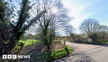The entrance to a closed golf course, showing a driveway surrounded by trees.
