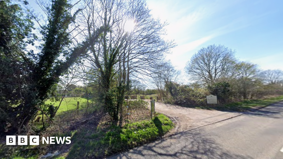The entrance to a closed golf course, showing a driveway surrounded by trees.
