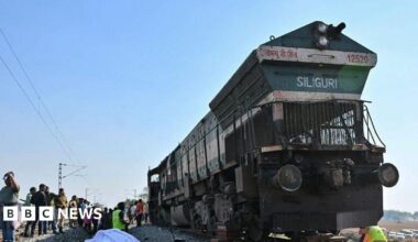 A covered elephant body lies along railway tracks  in the Hojai district, Assam state, as police and railway officials examine the scene. Photo: 20 December 2025