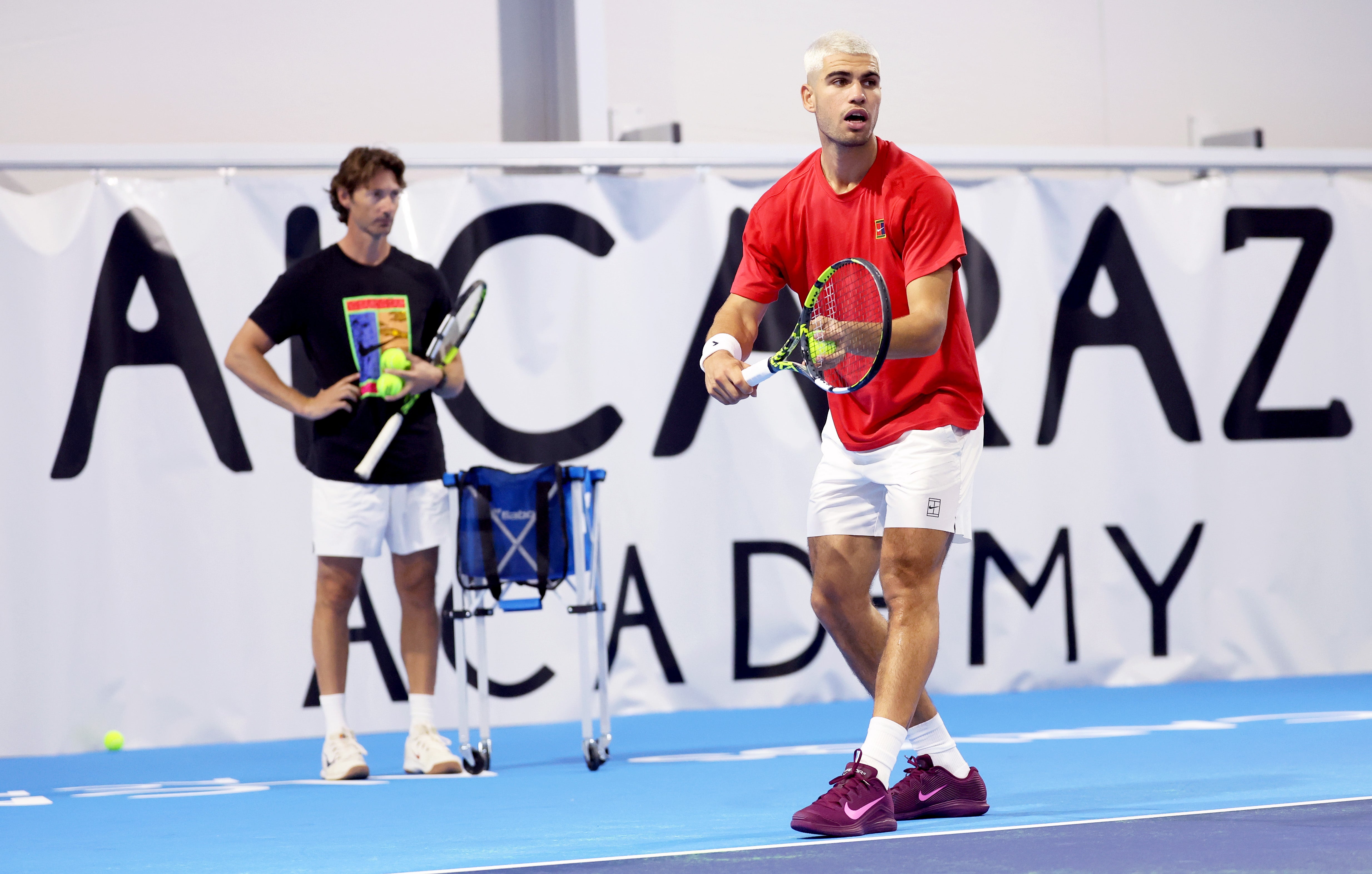 Carlos Alcaraz of Spain serves while being watched by his coach at the time Juan Carlos Ferrero