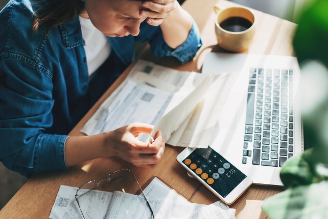 Woman accountant use calculator and computer with holding pen on