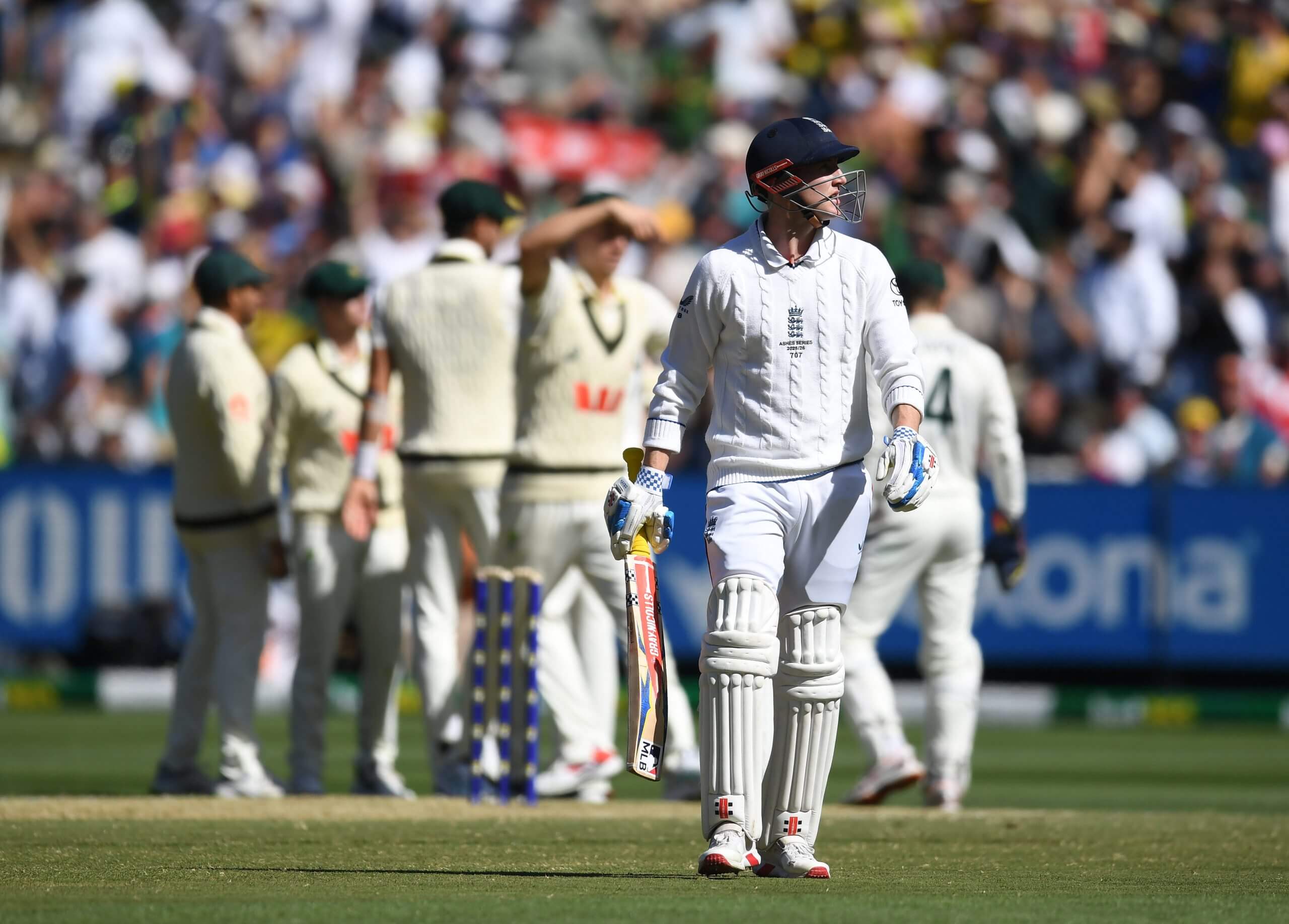 Australia gather in a huddle to celebrate as Harry Brook watches his dismissal back on the big screen
